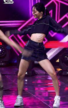 a woman in black shirt and skirt dancing on stage