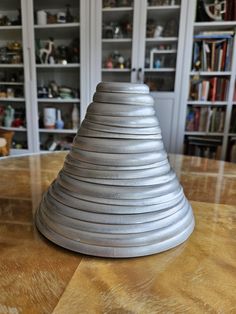 a metal cone sitting on top of a wooden table next to a book shelf filled with books