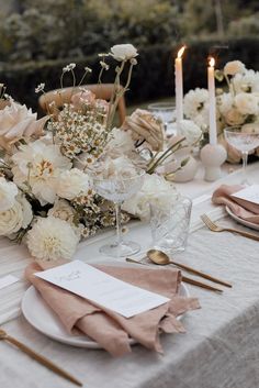 the table is set with white flowers and gold place settings for an elegant wedding reception