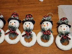 four snowmen with hats and wreaths sitting on top of a wooden table next to each other