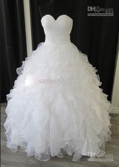 a white wedding dress with ruffles on the skirt