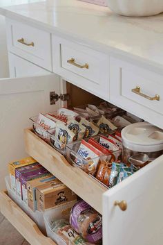 an open drawer in a white kitchen filled with food