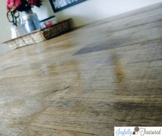 a wooden table that has some flowers on it and a vase with pink roses in the background