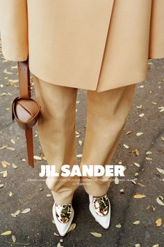 a person in tan pants and white shoes holding a brown bag with the words jl sander on it