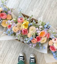 someone is standing next to some flowers on the floor