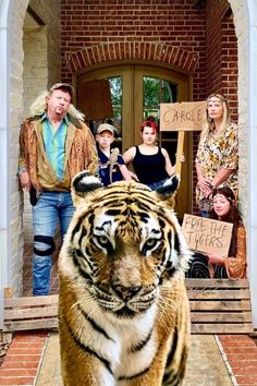 people are standing in front of a door with a tiger on the steps and one is holding a sign