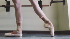 a ballerina's feet and ballet shoes in front of a wall with bars