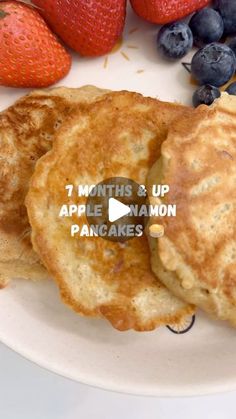 two pancakes on a plate with blueberries and strawberries