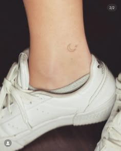 a woman's foot with a small crescent tattoo on the side of her ankle