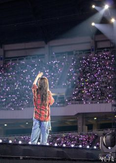 a woman standing on top of a stage in front of a crowd at a concert