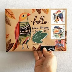 someone is holding up a small postcard with stamps on it that have birds and leaves