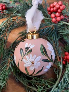 a pink ornament decorated with white flowers and greenery