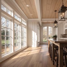 an empty kitchen with wood floors and large windows on the wall, along with bar stools