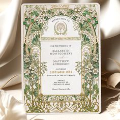 an ornate wedding card with flowers and vines on the front, in gold foiling