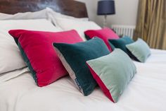 teal and grey cushions with other coloured cushions on white bedding Dark Pink Velvet, Purple Cushions