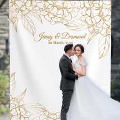 a bride and groom standing next to each other in front of a white backdrop with gold leaves