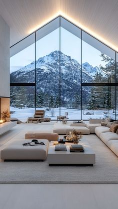 a modern living room with large windows overlooking the mountains and snow covered trees in winter