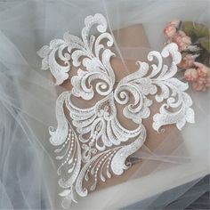 a piece of paper with white lace on top of it and flowers in the background