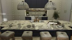 an image of a kitchen setting with marble counter tops and stools in the center