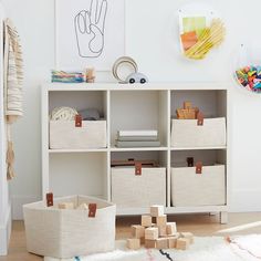 a white bookcase with baskets and toys on it in a child's room