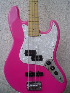 a pink bass guitar hanging on the wall