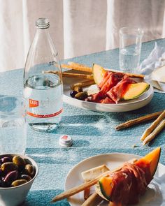 a table topped with plates and bowls filled with different types of food next to bottles of water