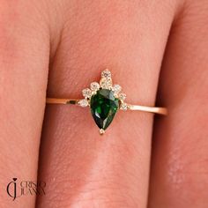 a woman's hand with a green and white diamond ring on her left finger