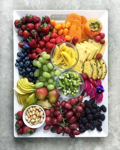 a platter filled with fruits and vegetables on top of a white plate next to nuts