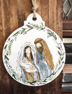 a ceramic ornament hanging on the side of a wooden door with a nativity scene painted on it