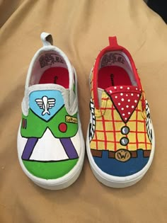 two pairs of shoes with colorful designs on them sitting on top of a bed next to each other