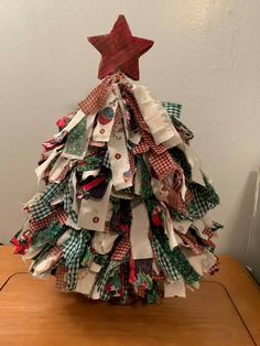 a christmas tree made out of old clothes on top of a wooden table next to a wall