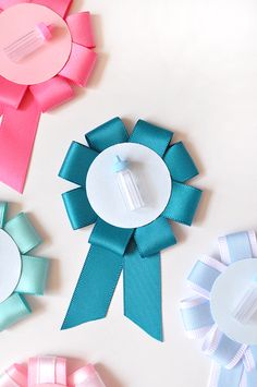 four different colored ribbons are arranged on a white surface, one with a bottle in the center