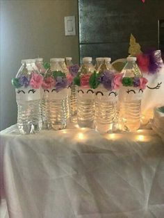 a table topped with lots of water bottles filled with flowers and unicorn face masks on top of it