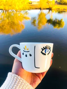 a hand holding a coffee cup with eyes painted on it