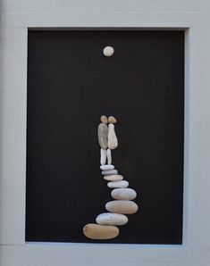 a white frame with some rocks in the shape of a person and a ball on top