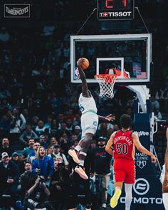 the basketball player is going to dunk the ball in front of the other player