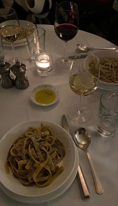 a white table topped with pasta and wine glasses