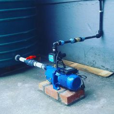 a blue and black pipe sitting on top of a brick block next to a water tank