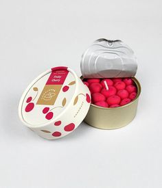 two tins filled with pink and red balls on a white surface, next to each other