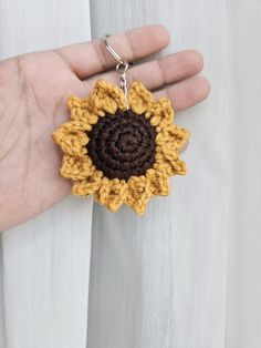 a crocheted sunflower keychain hanging from a person's hand