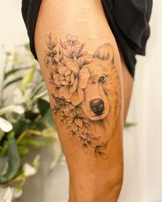 a close up of a person's leg with flowers and a bear on it