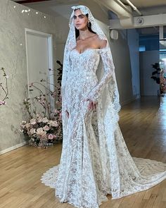 a woman in a white wedding dress standing on a wooden floor with her veil draped over her head