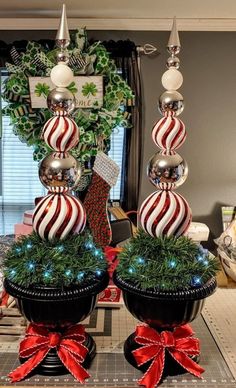 two christmas decorations on top of each other in black pots with red and white balls