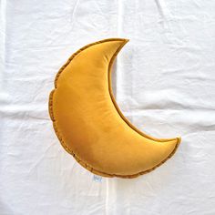 a yellow crescent pillow sitting on top of a white sheet