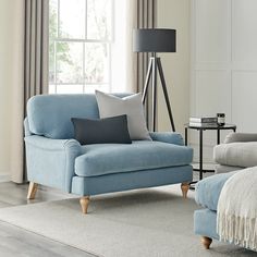 a living room scene with focus on the blue couch and pillows in front of the window