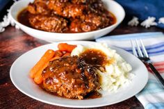 two white plates topped with meatballs and carrots next to mashed potatoes on a wooden table