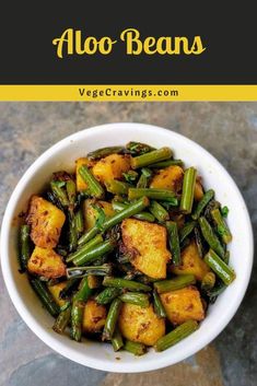 a white bowl filled with cooked green beans and tofu on top of a table