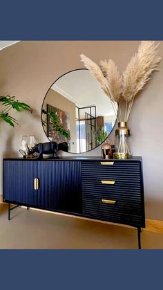 a black and gold sideboard with a mirror on the wall next to some plants