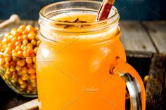 an orange drink in a mason jar next to a bowl of corn on the table