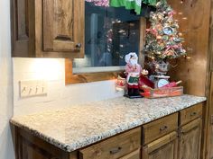 a kitchen counter with a christmas tree on top and other decorations in the window sill